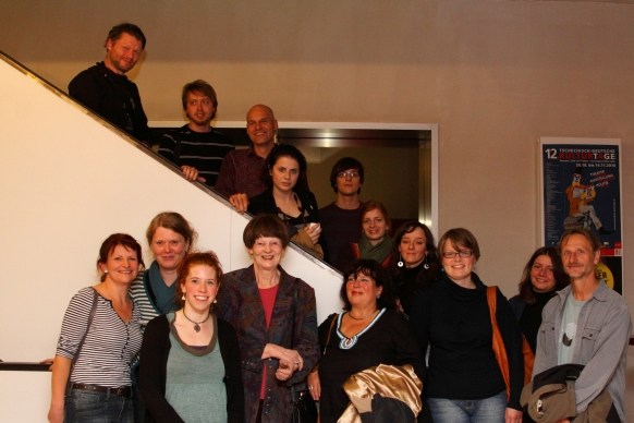 15 Personen auf der Treppe im Programmkino Ost: Organisator*innen, Filmschaffende und Gäste der FEINKOŠT-Premiere. 