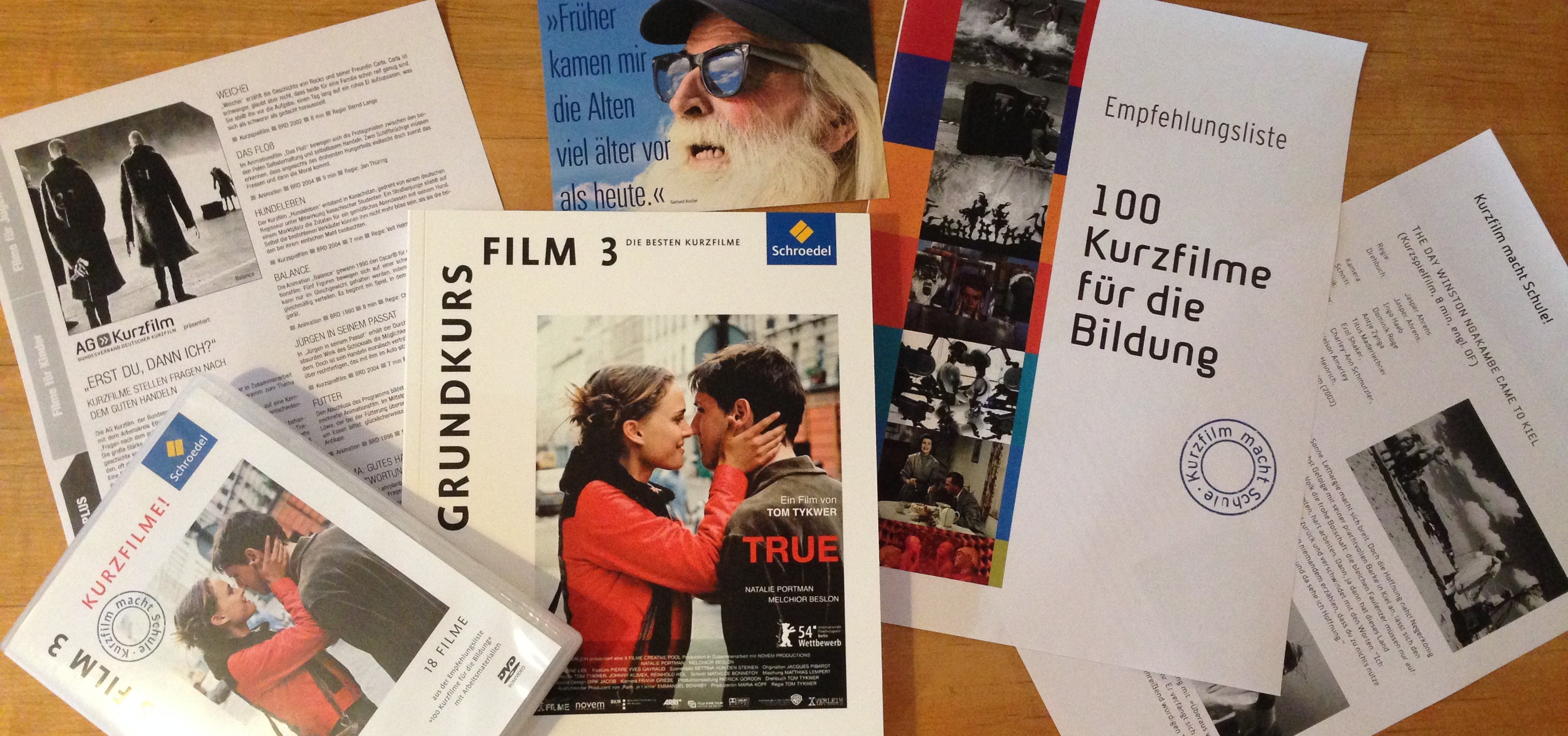 Auf einem Tisch liegen Hefte, Flyer und eine DVD ausgebreitet. Auf einem steht „100 Kurzfilme für die Bildung“.